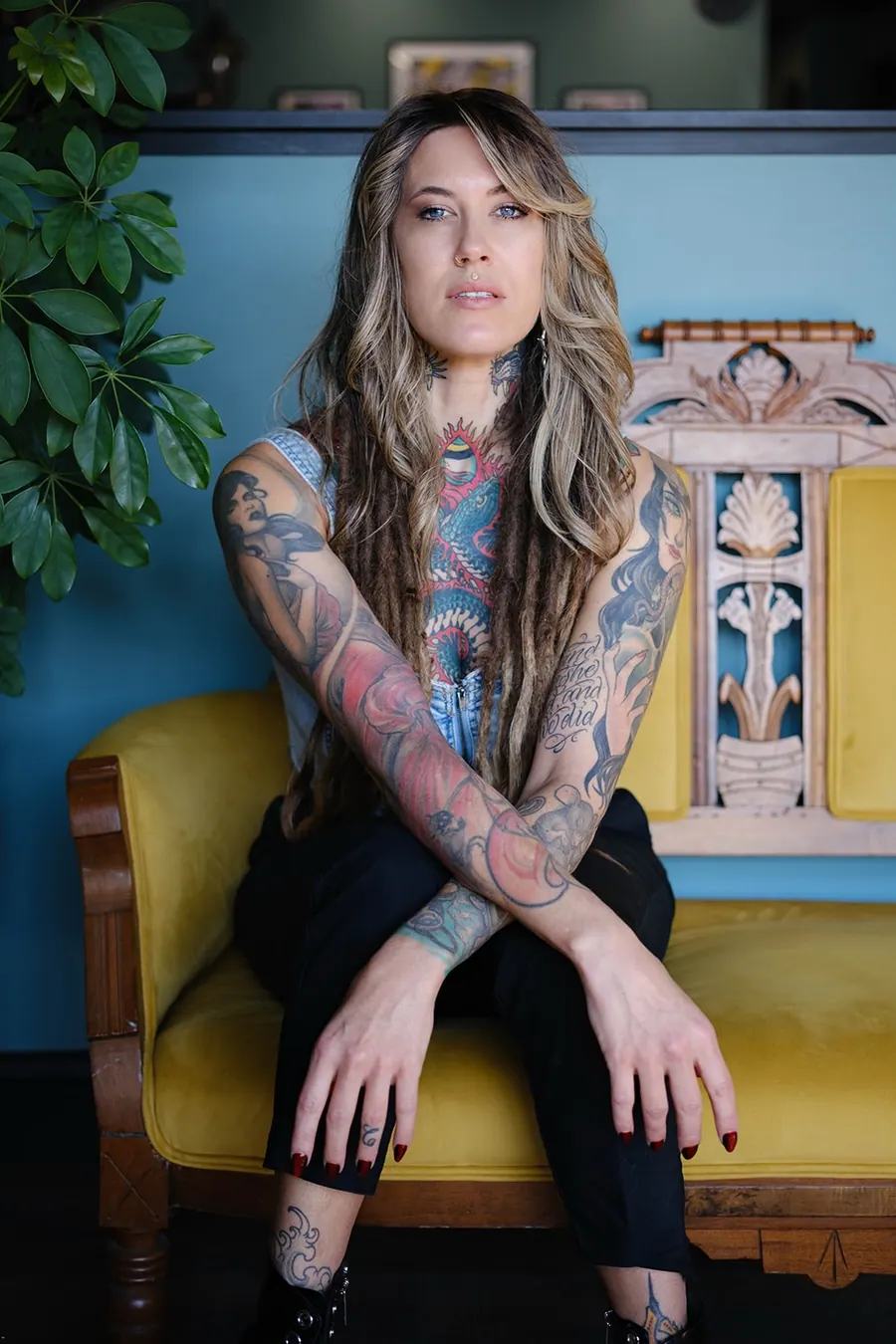 English Cousins seated on a yellow velvet settee at Pilgrimage Tattoo, arms crossed, looking into the camera