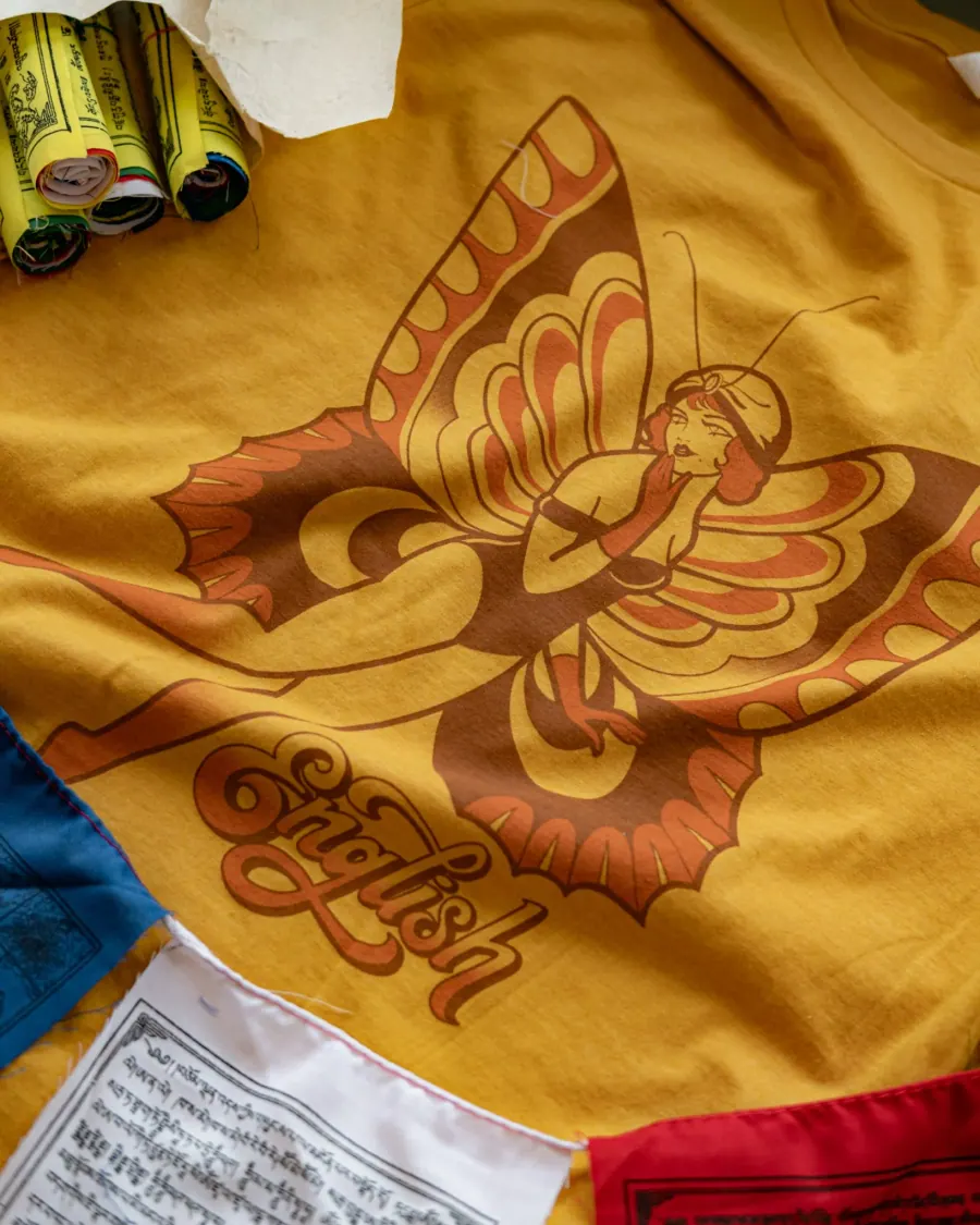 A yellow T-shirt featuring a vintage-style illustration of a woman with butterfly wings and the text Feminist