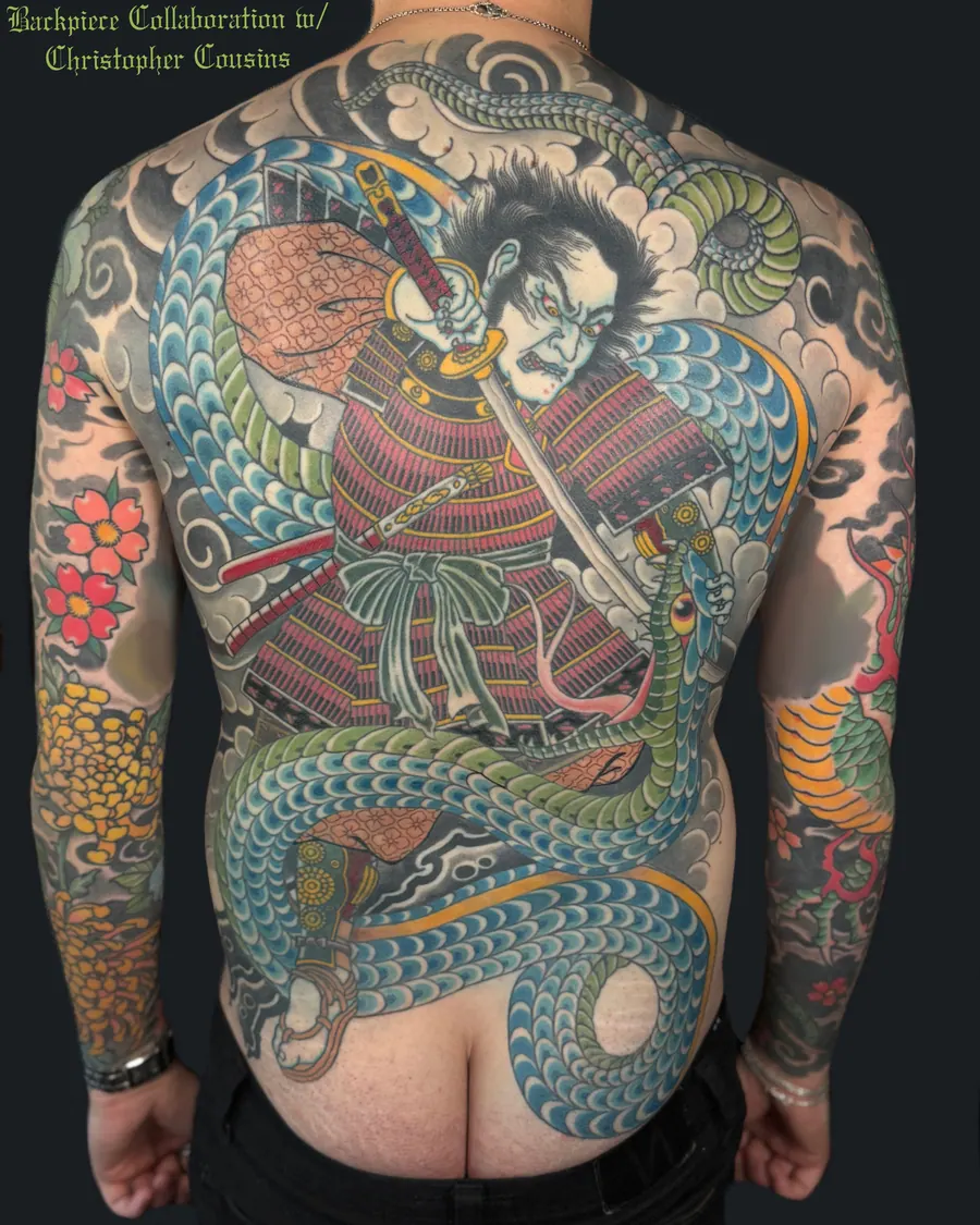 Japanese backpiece of a samurai drawing his sword, wrapped in a great blue and green serpent among clouds and cherry blossoms, a collaboration with Christopher Cousins, by English Cousins, Nashville