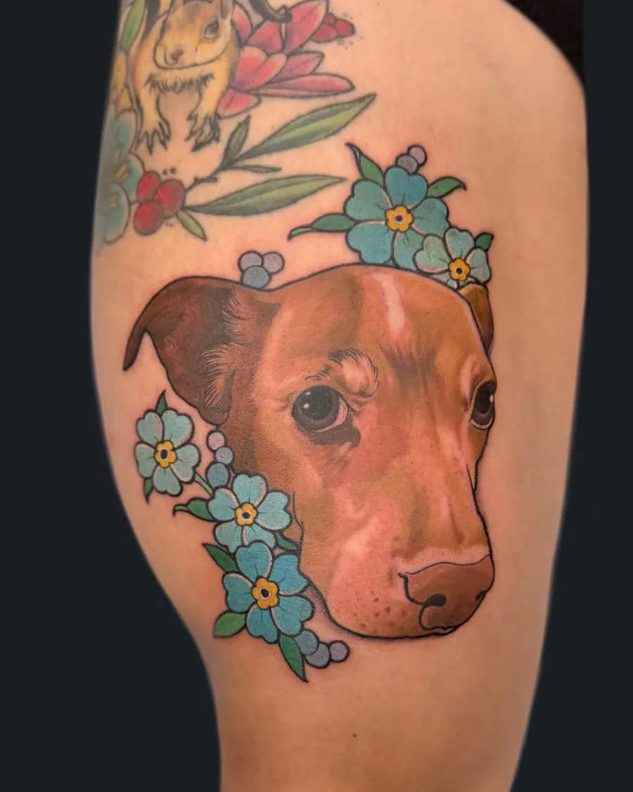Color pet portrait tattoo of a brown dog surrounded by blue forget-me-not flowers by English Cousins, Nashville