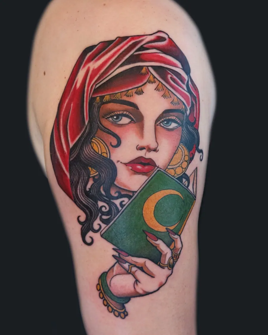 Neotraditional tattoo of a woman with dark wavy hair and a red headscarf holding a green tarot card with a gold crescent moon by English Cousins, Nashville