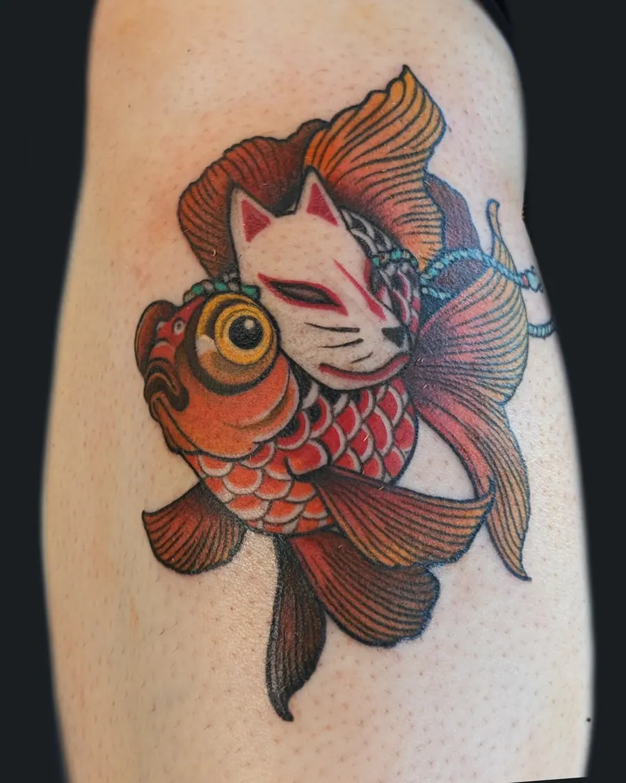 Neotraditional goldfish wearing a white kitsune fox mask, tattooed on the upper arm by English Cousins, Nashville
