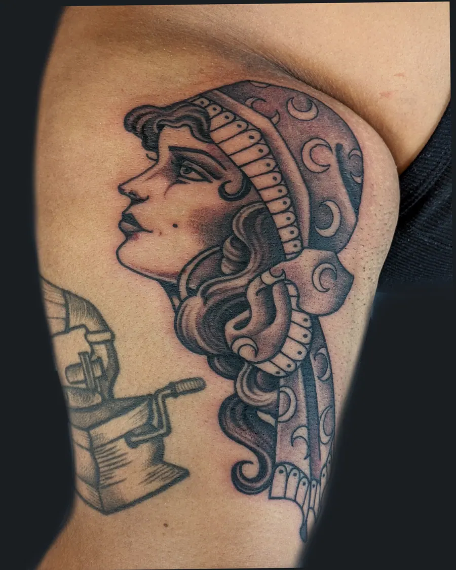 Black and gray tattoo of a woman in profile wearing a crescent-moon headscarf on the inner arm by English Cousins, Nashville