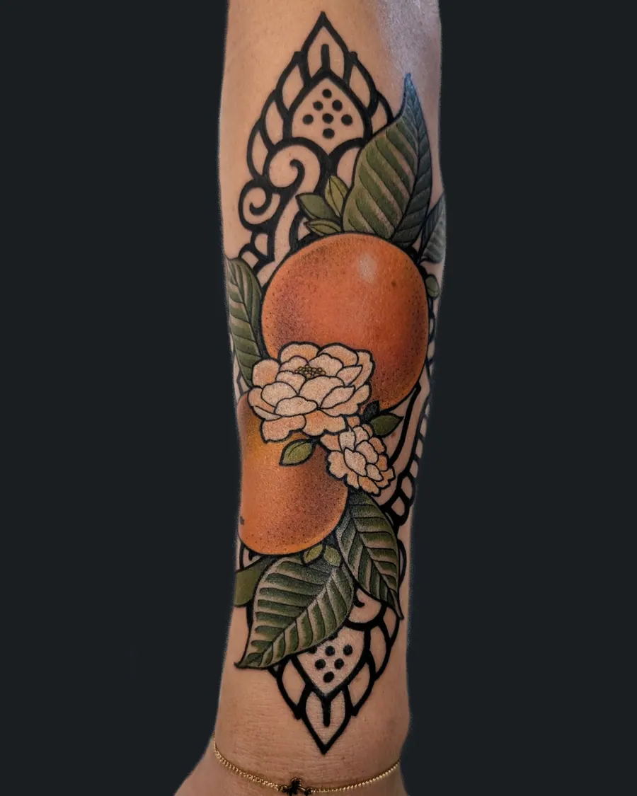 Tattoo of oranges and blossoms on the forearm with black ornamental patterns behind them by English Cousins, Nashville