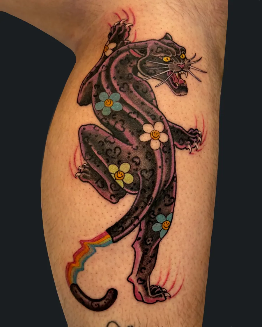 Neotraditional black panther tattoo with smiley-face daisies and a rainbow tail on the calf by English Cousins, Nashville