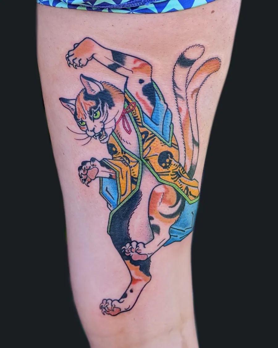 Japanese-style calico cat in a patterned kimono, mid-leap, tattooed on the thigh by English Cousins, Nashville